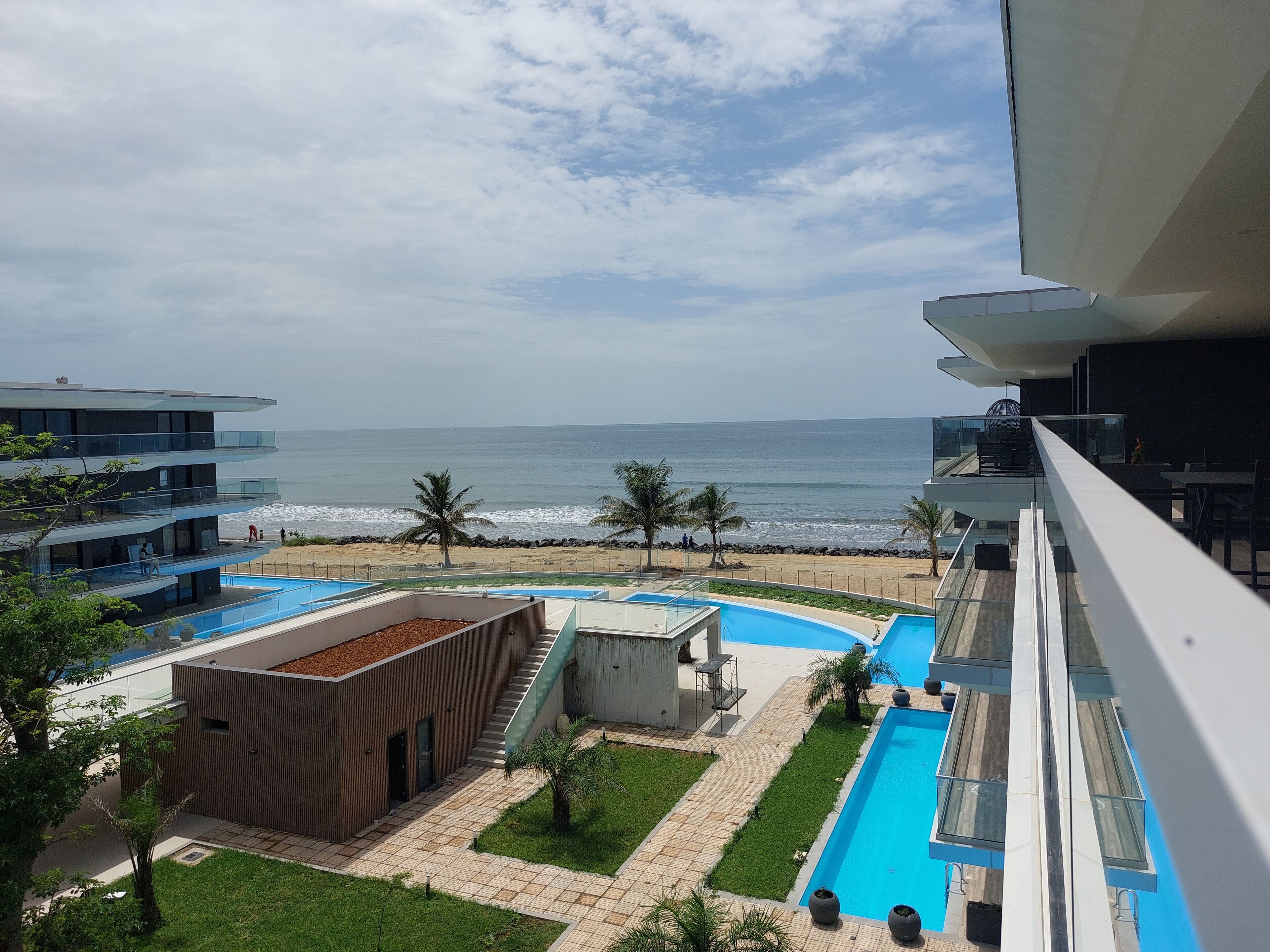 A modern hotel with a rooftop pool, a view of the beach, and a clear sky.