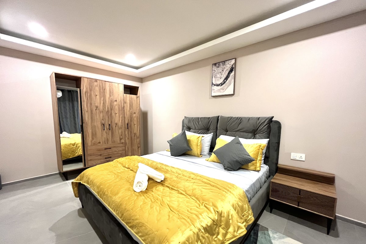 Un dormitorio con cama, armario, mesita de noche y una obra de arte colgada en la pared.