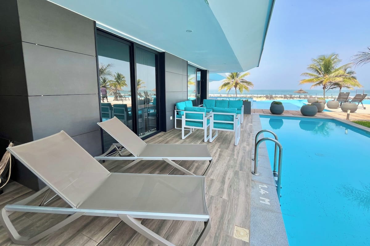 Un área de piscina moderna con sillones de descanso y vistas a la playa.