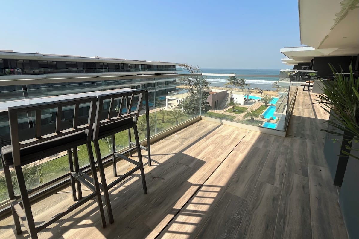 Un balcón con vista al océano y una zona de piscina.