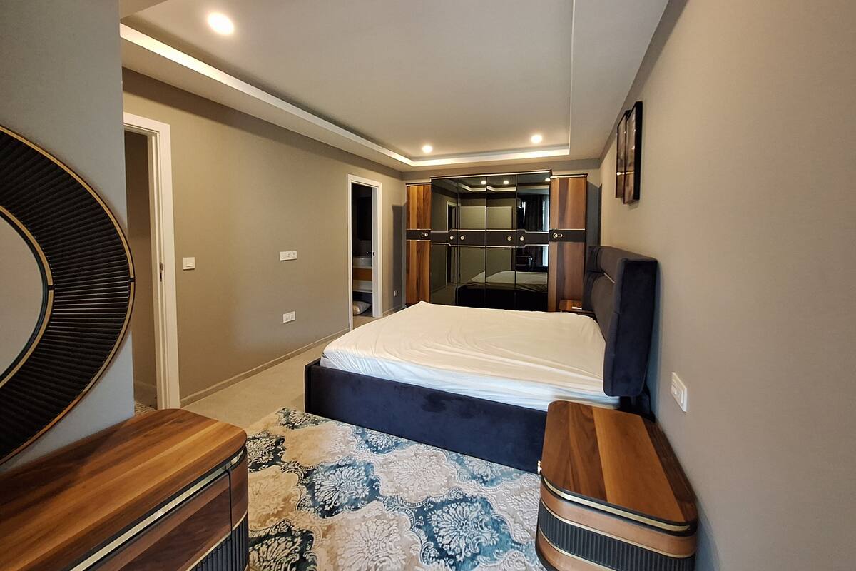 Un dormitorio con cama, cómoda, espejo, armario y mesita de noche.