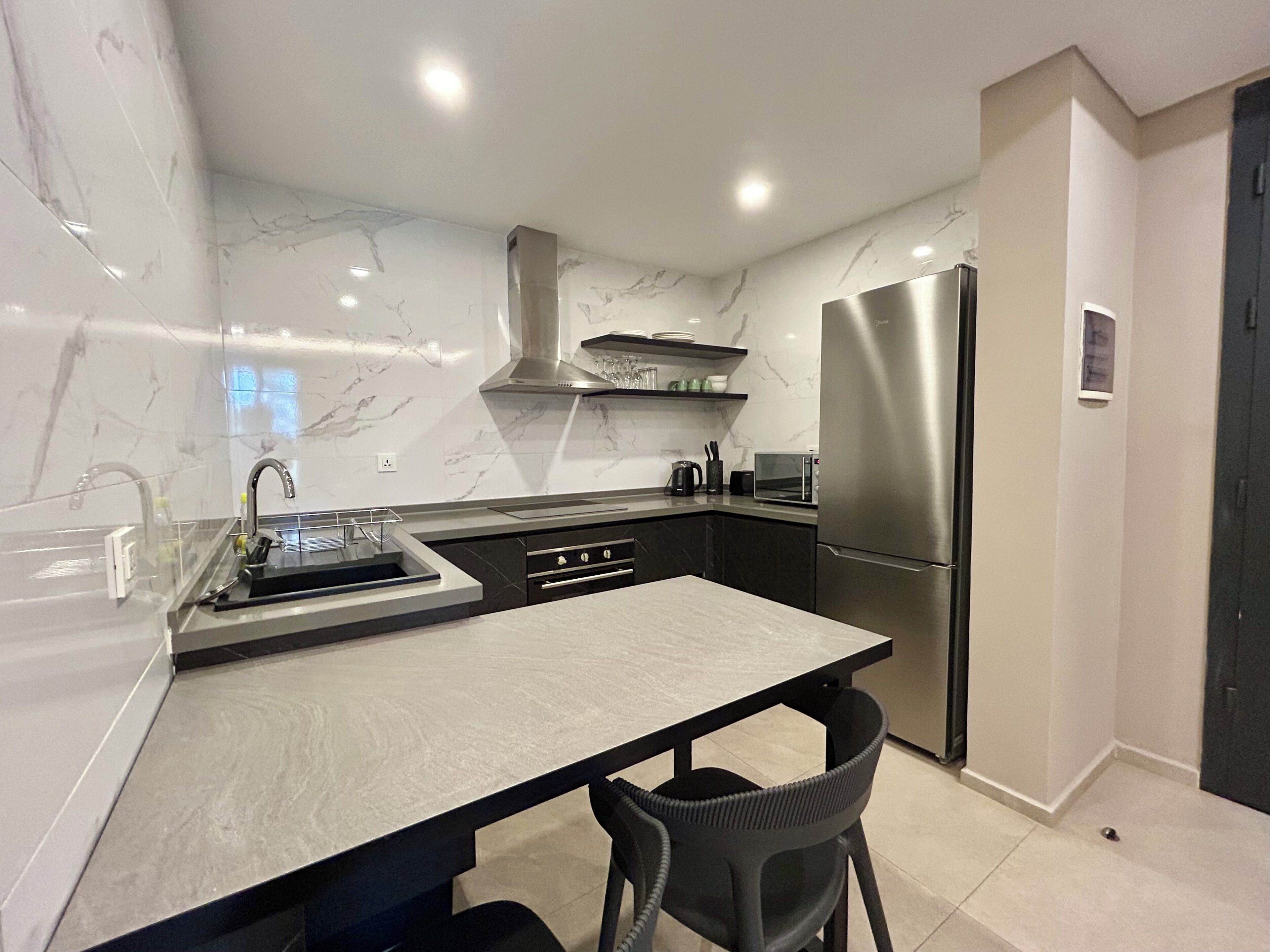 Una cocina moderna con salpicadero de mármol, electrodomésticos de acero inoxidable y una isla central con asientos.