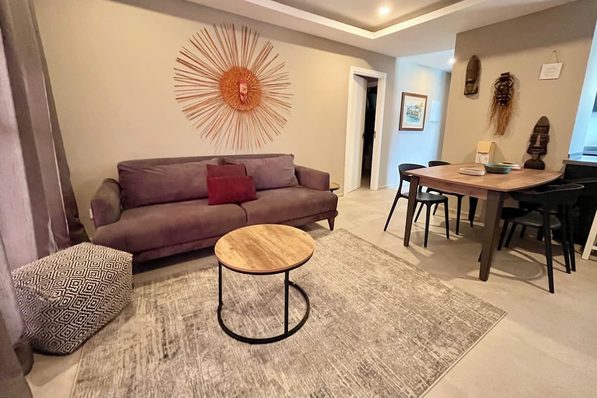 Una sala de estar moderna con sofá, mesa de centro redonda y comedor con sillas y una mesa.