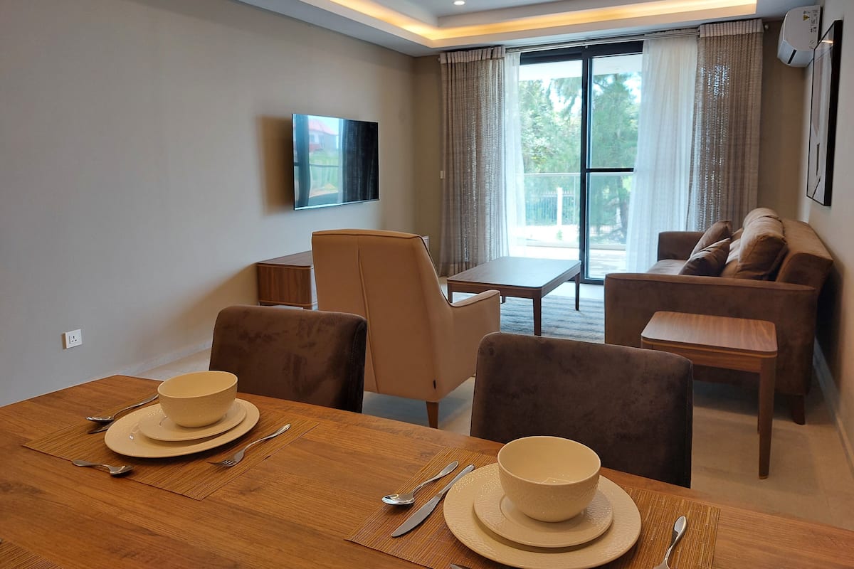 Una sala de estar moderna con comedor, un juego de sofá y un televisor montado en la pared.