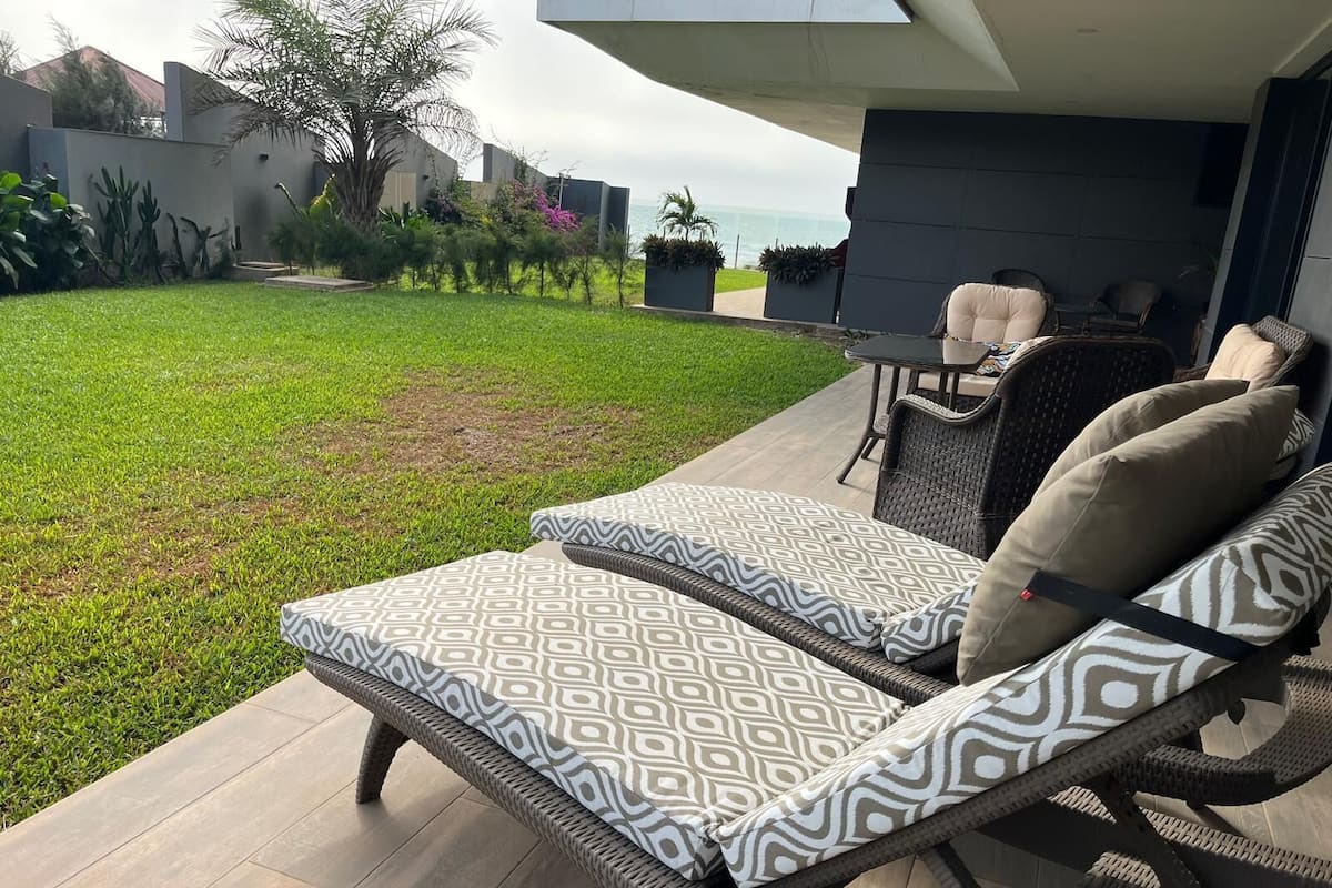 Un patio con dos sillones de descanso, una mesa y vista al océano.