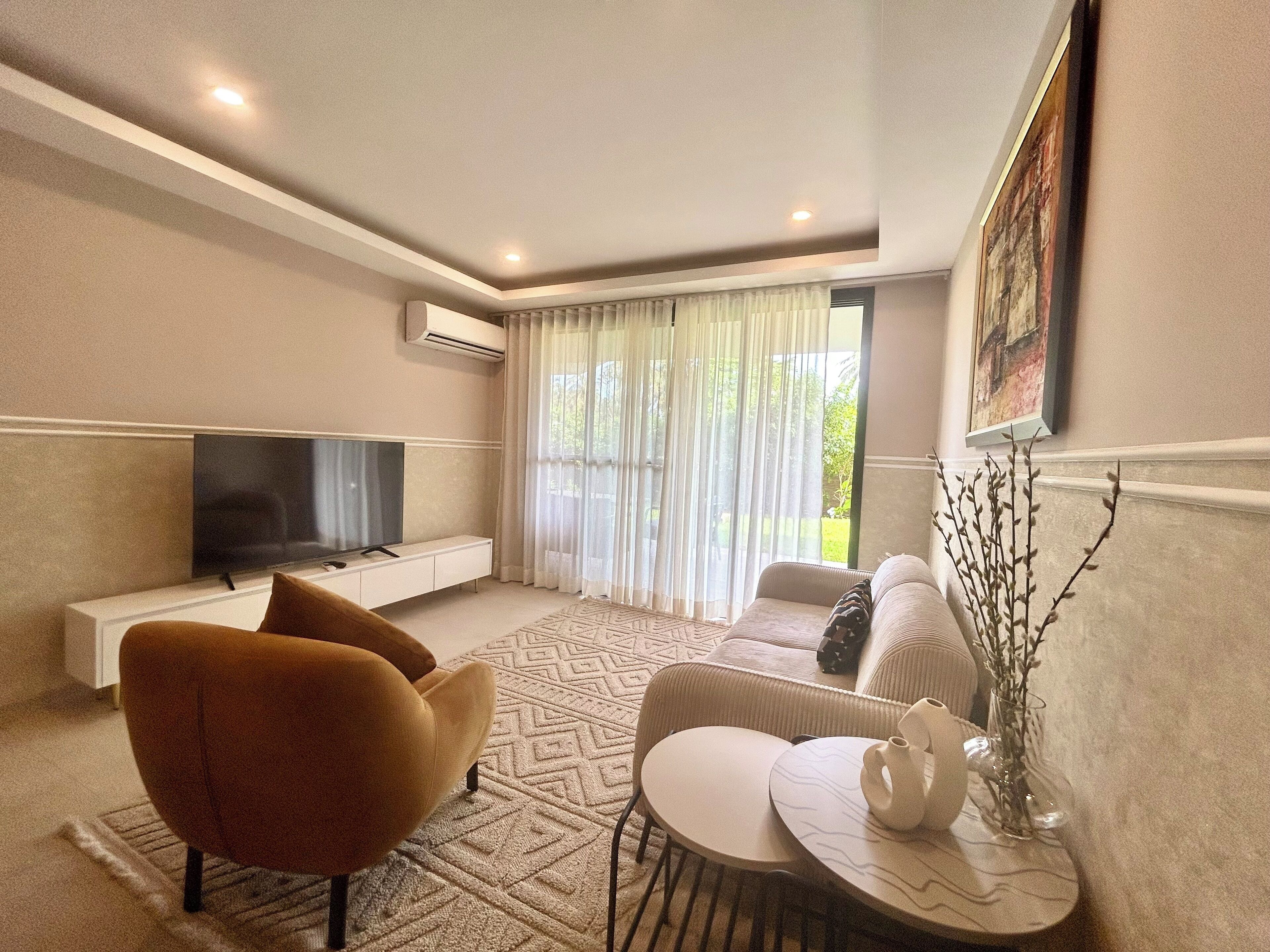 A modern living room with a flat-screen TV, a sofa, a coffee table, and a decorative vase.