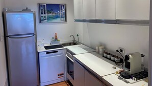 A compact kitchen with a refrigerator, dishwasher, and coffee machine. - HOUSE OLEANDRI 200m from the beach (PUNTA ALA)