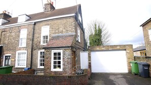 A two-story brick house with a garage, a small garden area, and a visible chimney. - Immaculate 3-bed House in Waltham Cross (Waltham Cross)