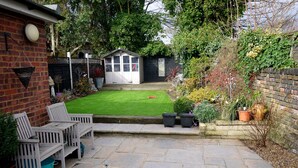 A patio with a lawn, a small shed, and a brick wall. - Immaculate 3-bed House in Waltham Cross (Waltham Cross)