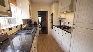 A kitchen with white cabinetry, a black countertop, and a stainless steel range hood. - Immaculate 3-bed House in Waltham Cross (Waltham Cross)