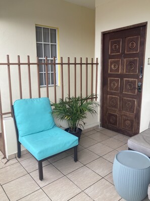 A blue chair, a potted plant, and a round blue table on a tiled patio.