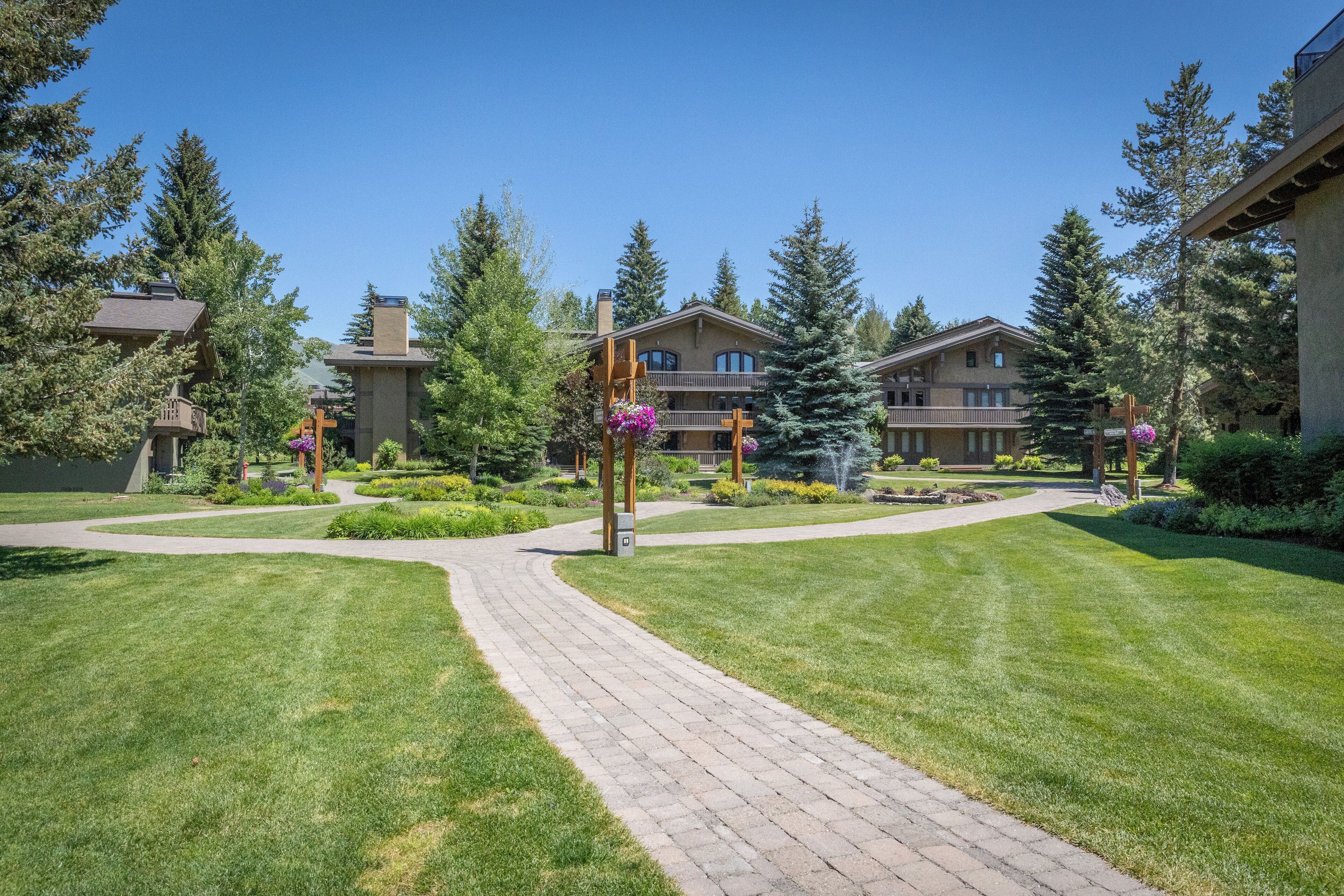 A courtyard with a paved walkway, surrounded by well-maintained lawns and trees.