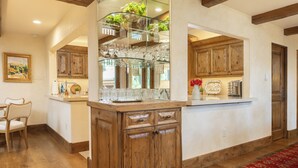 A kitchen with wooden cabinets, a glass display shelf, and a red patterned rug. - Sun Valley retreat at Lodge II Condos with garage and Resort Amenities (Sun Valley)