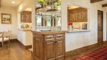 A kitchen with wooden cabinets, a glass display shelf, and a red patterned rug.