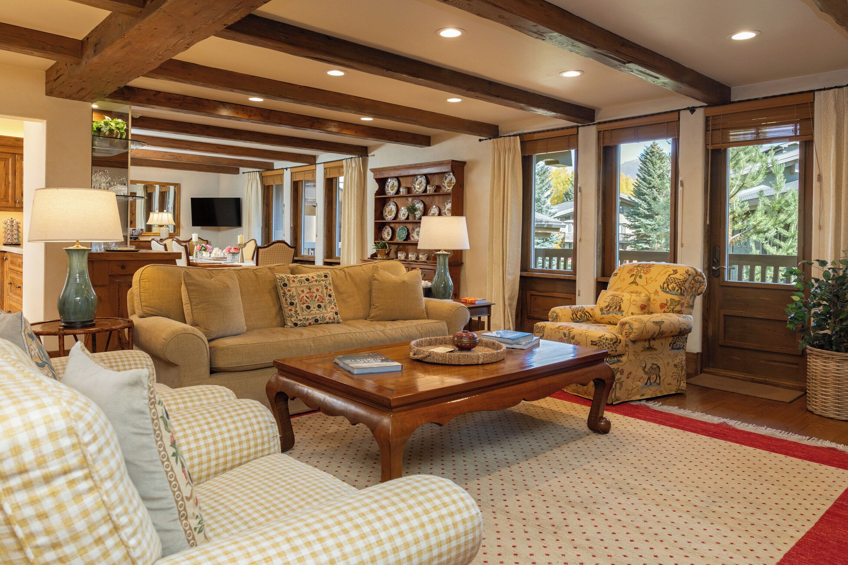 A cozy living room with a wooden coffee table, checkered sofas, and a yellow armchair.