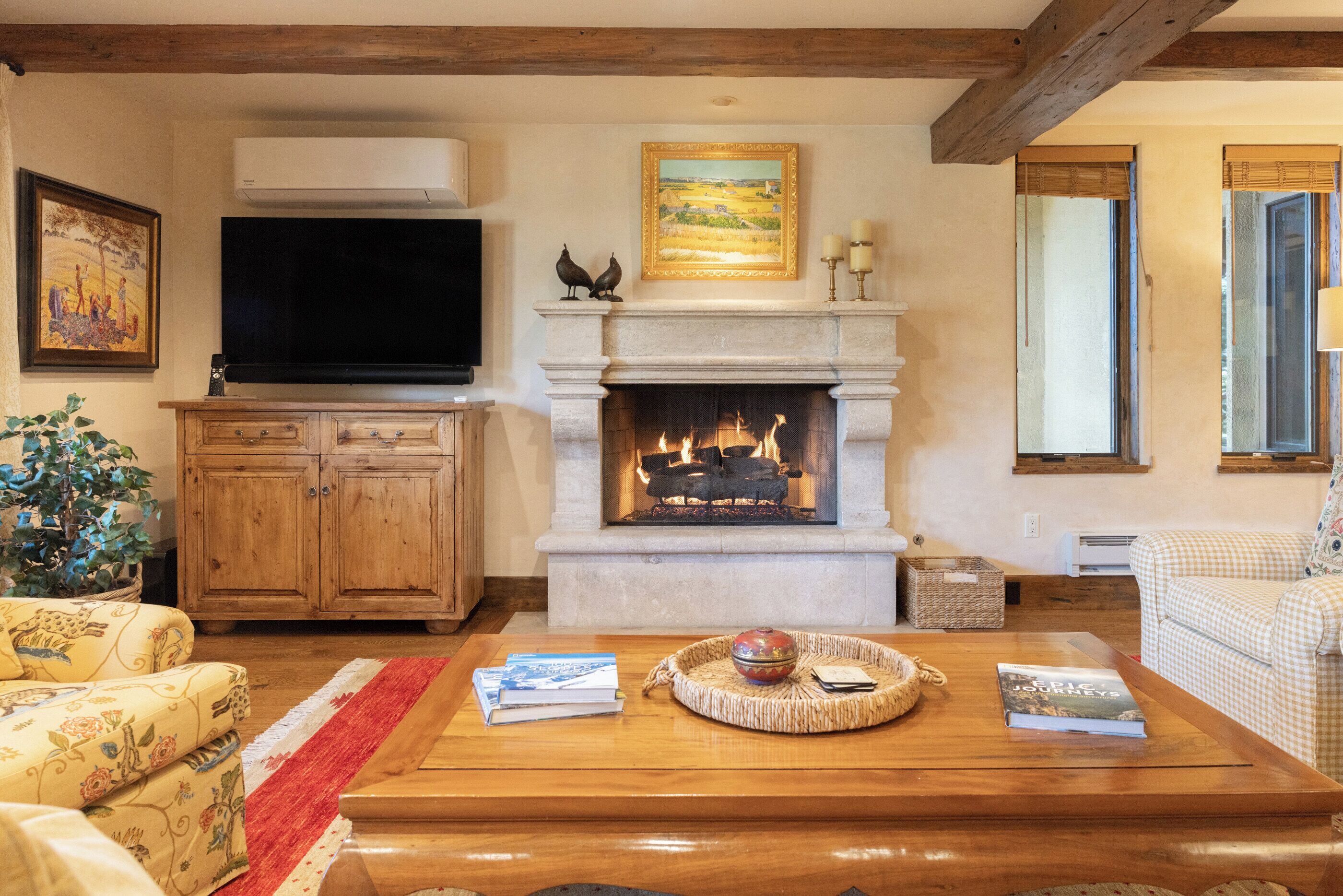 A living room with a fireplace, wooden furniture, a television, and a painting on the wall.