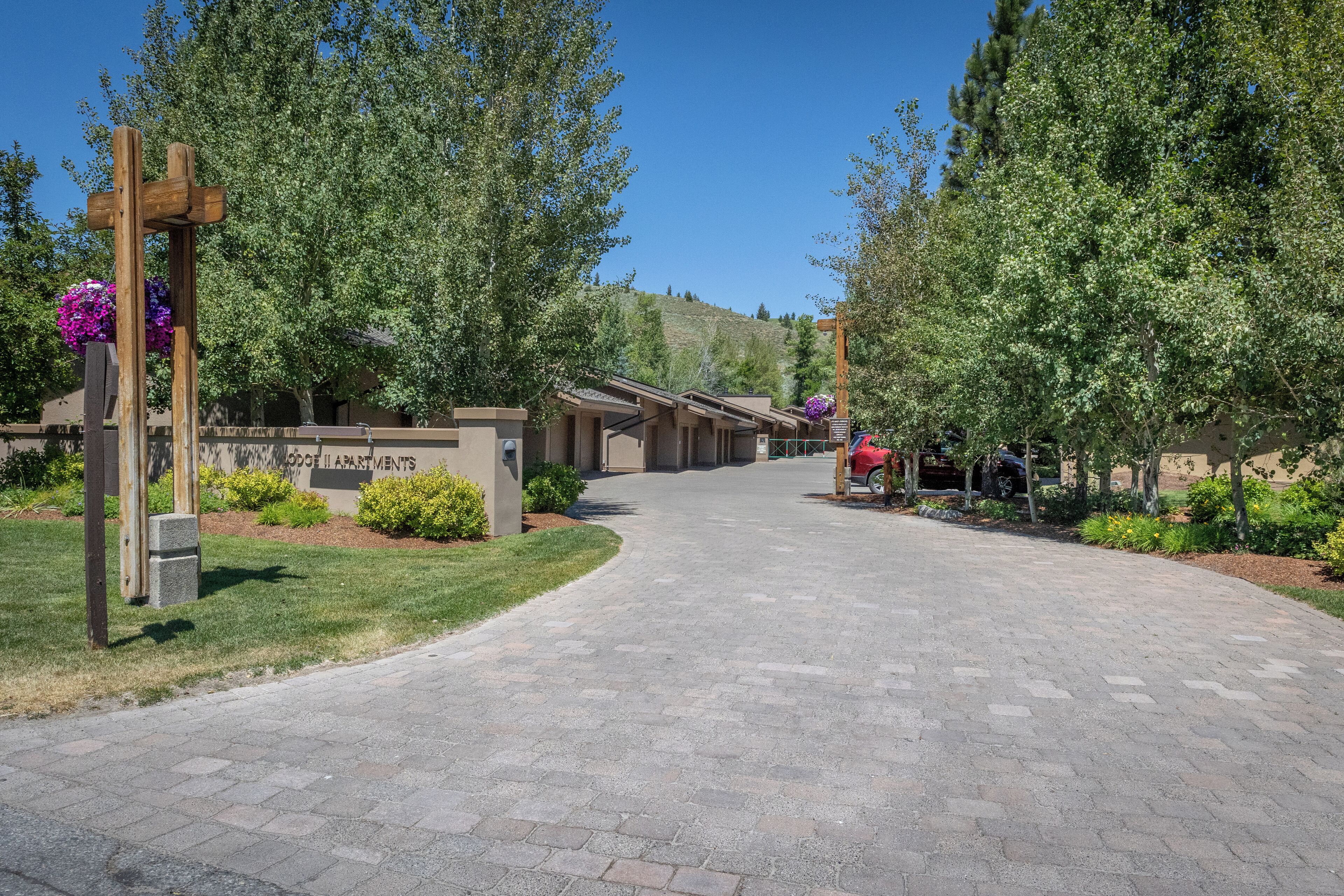 A paved driveway leading to a building with a sign reading "ROOF II APARTMENTS".