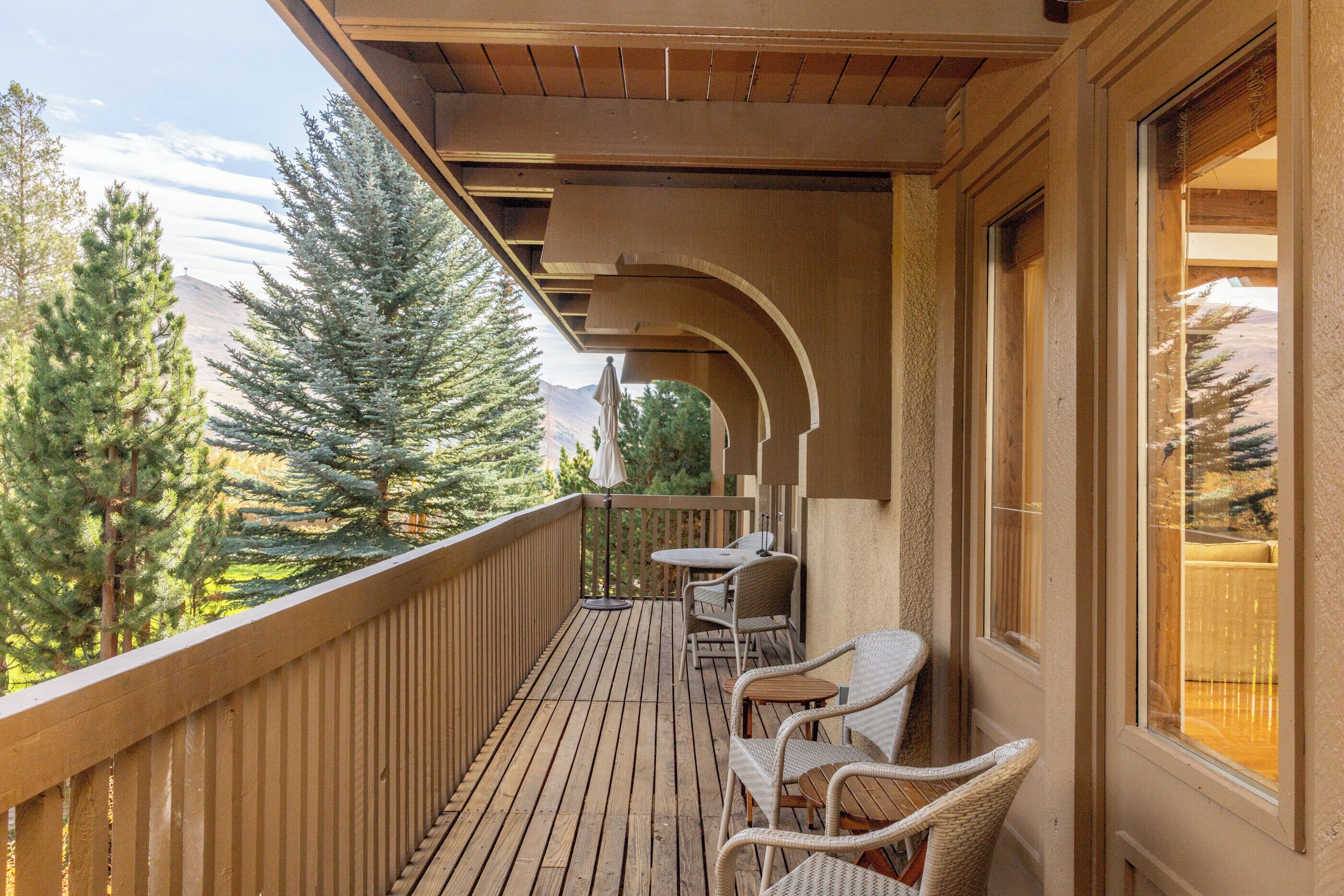 A wooden deck with outdoor seating and a view of trees and mountains.