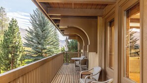 A wooden deck with outdoor seating and a view of trees and mountains. - Sun Valley retreat at Lodge II Condos with garage and Resort Amenities (Sun Valley)
