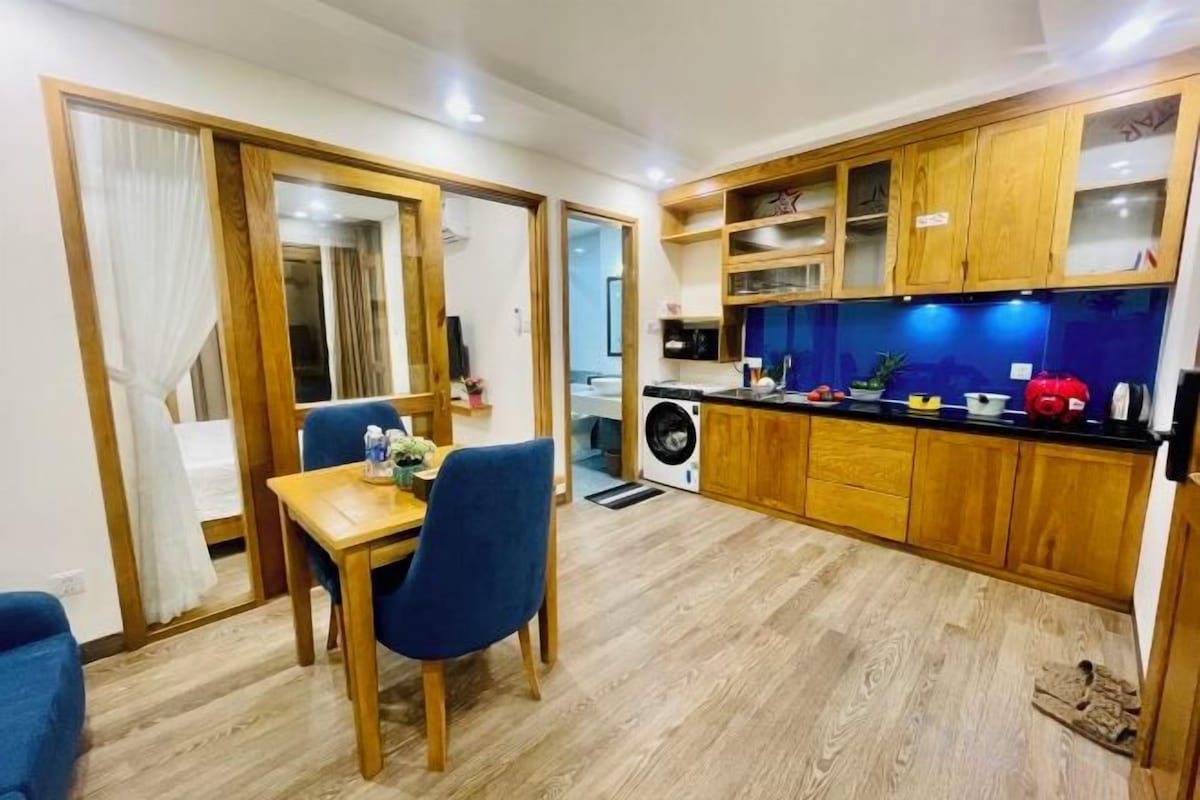 Cocina compacta con armarios de madera, una mesa de comedor con sillas y lavadora a la vista.