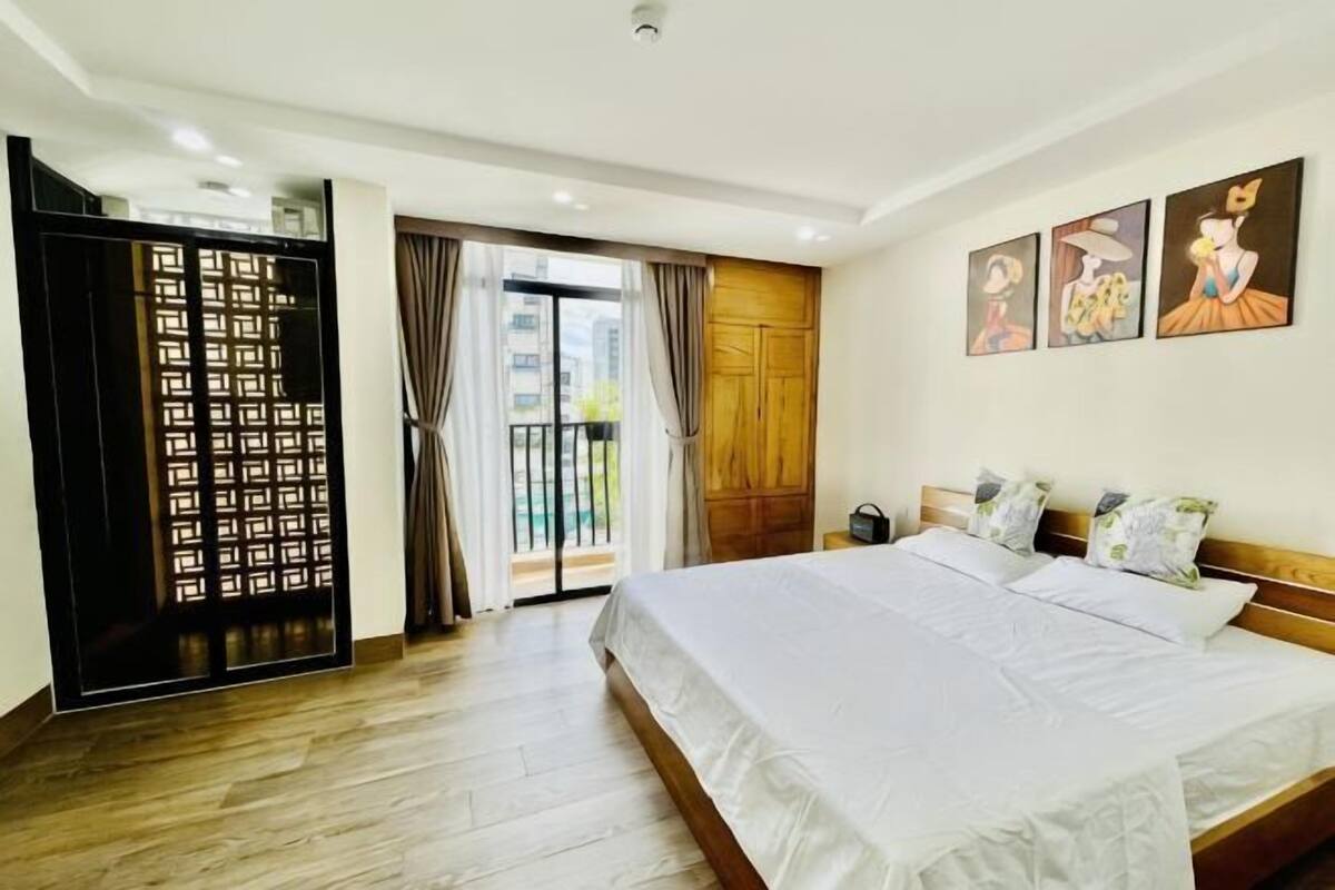 Ein Hotelzimmer mit einem großen Bett, einer Schiebetür und einem Balkon mit Vorhängen.