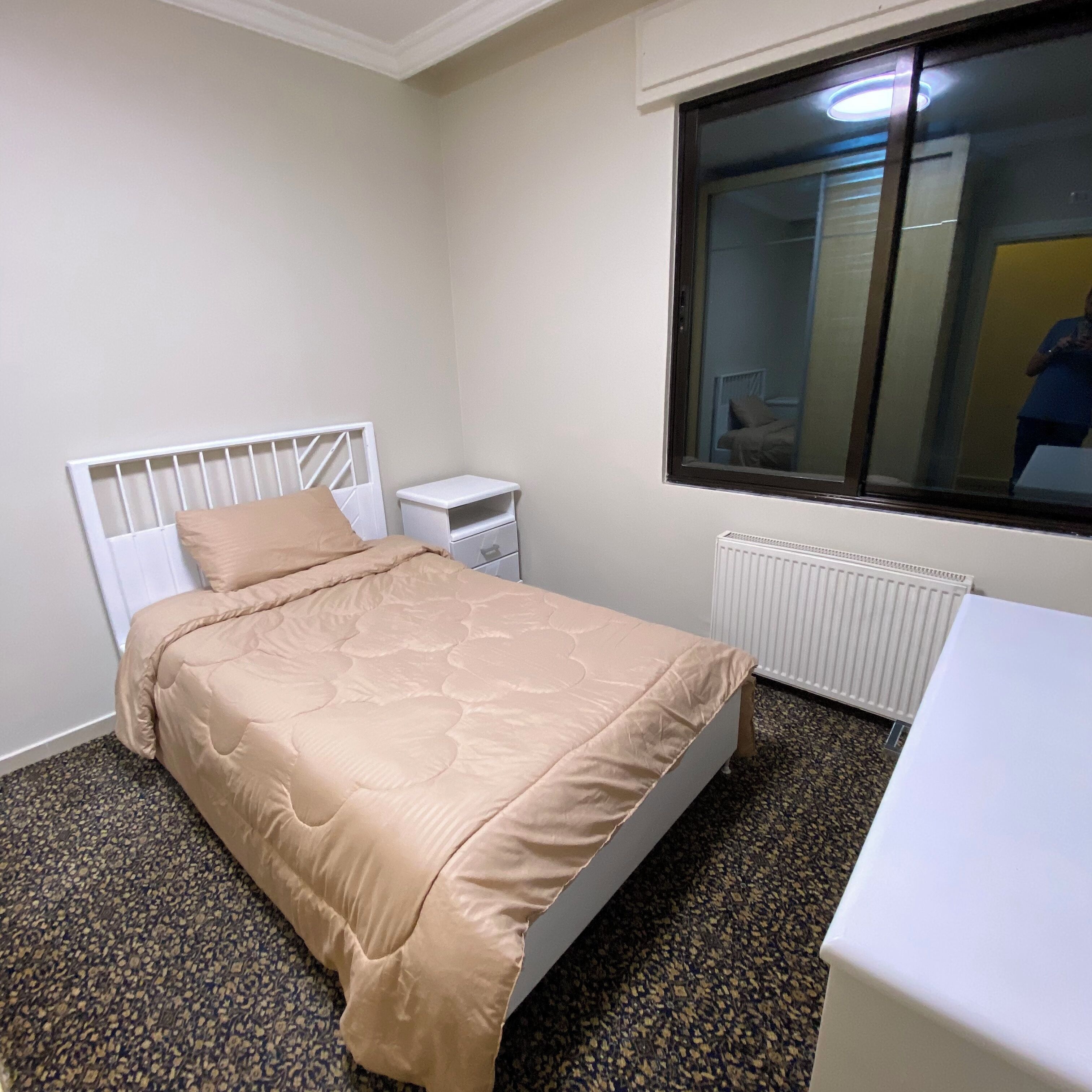 Ein Schlafzimmer mit Bett, Nachttisch und Fenster.