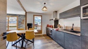 A modern kitchen with a dining area, wooden flooring, and a view of mountains through a large window. - Very nice apartment, 3 Bedrooms Very nice view (Val-d'Isère)