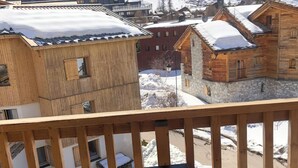 A balcony with a table set for breakfast, overlooking a snowy mountain landscape and traditional wooden buildings. - Very nice apartment, 3 Bedrooms Very nice view (Val-d'Isère)