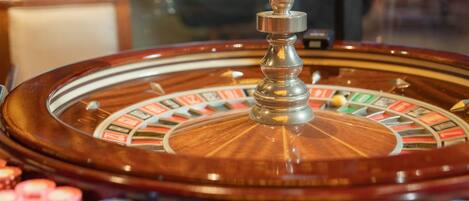 A roulette wheel with a central spinning spindle and a wooden table.