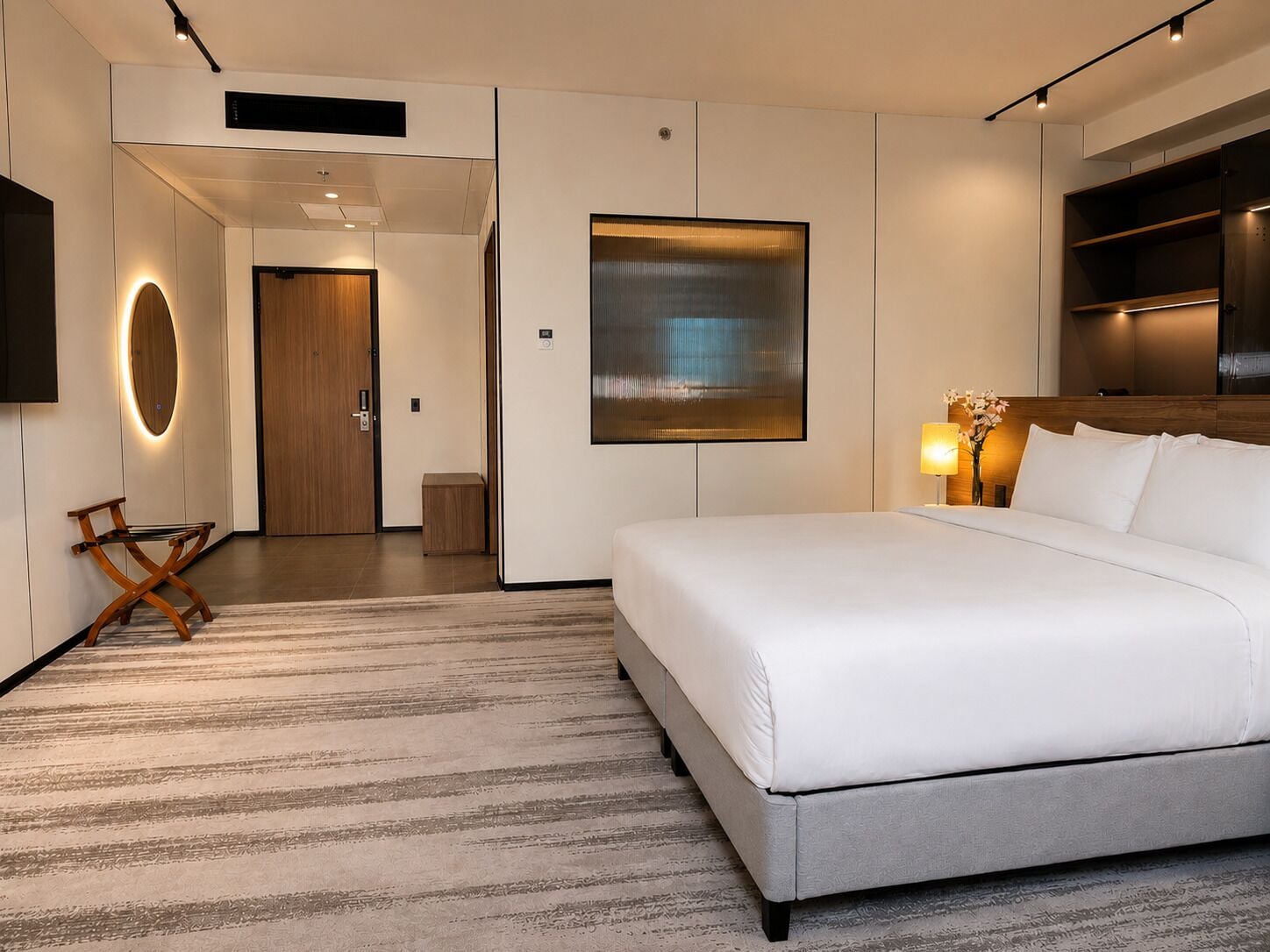 A modern hotel room with a large bed, a flat-screen TV, a wooden door, and a wall-mounted artwork.