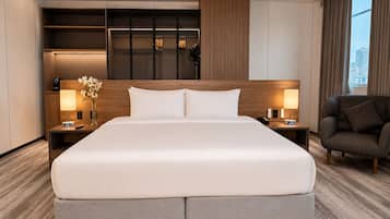 Un moderno cuarto de hotel con una cama grande, mesitas de noche, una silla y vistas a la ciudad.