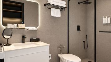 Un baño moderno con inodoro, lavamanos, espejo, toallero, ducha y artículos de aseo.