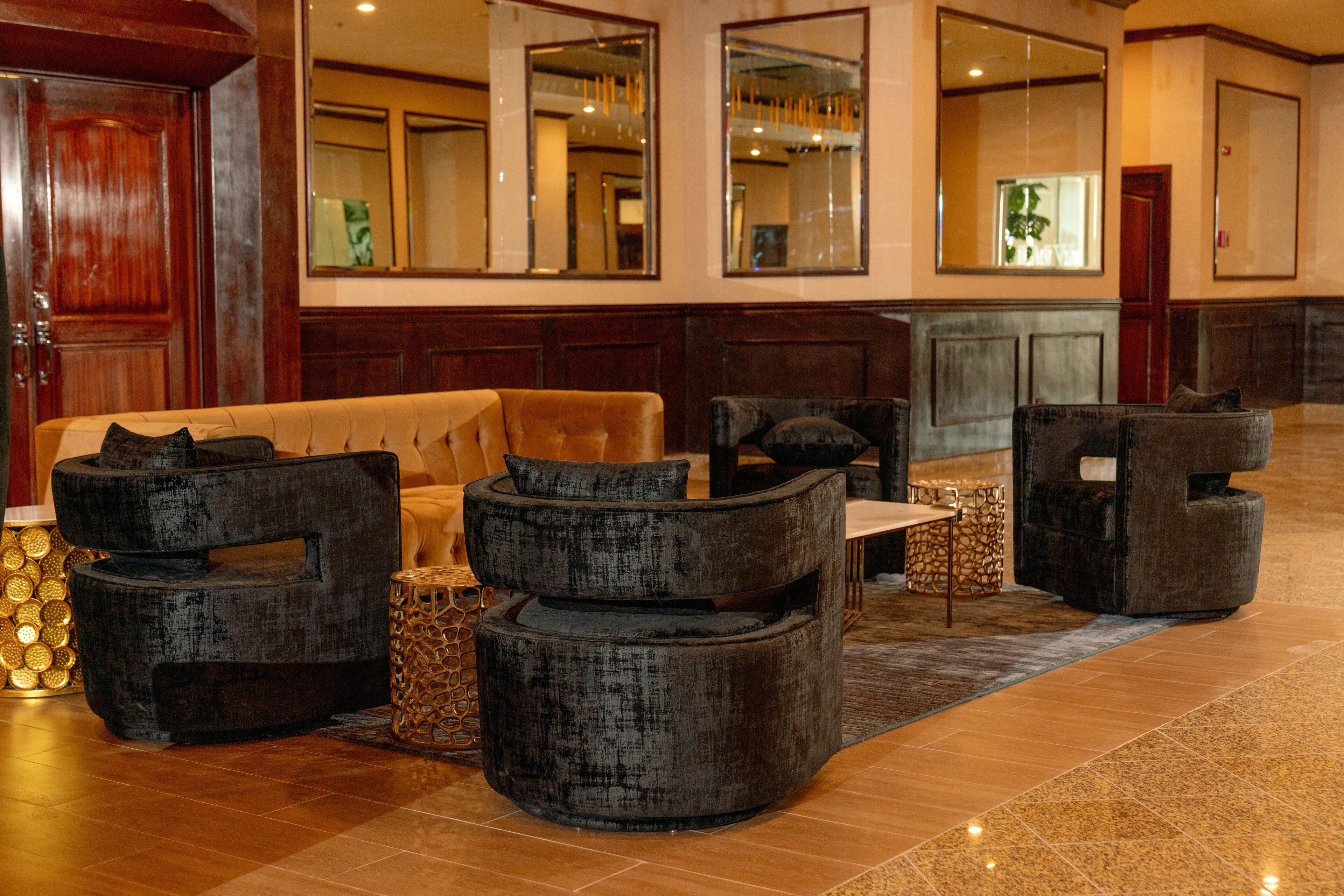 A lobby with a sofa, armchairs, a small table, and a decorative lamp.