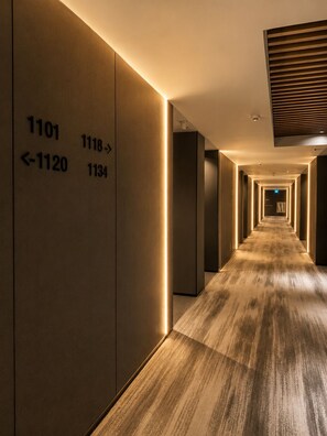 Un couloir d’hôtel avec des numéros de chambre lumineux, placés sur les murs, pour indiquer leur emplacement.