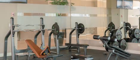 Ein Fitnessstudio mit Gewichte, Bänken und einer Spiegelwand.