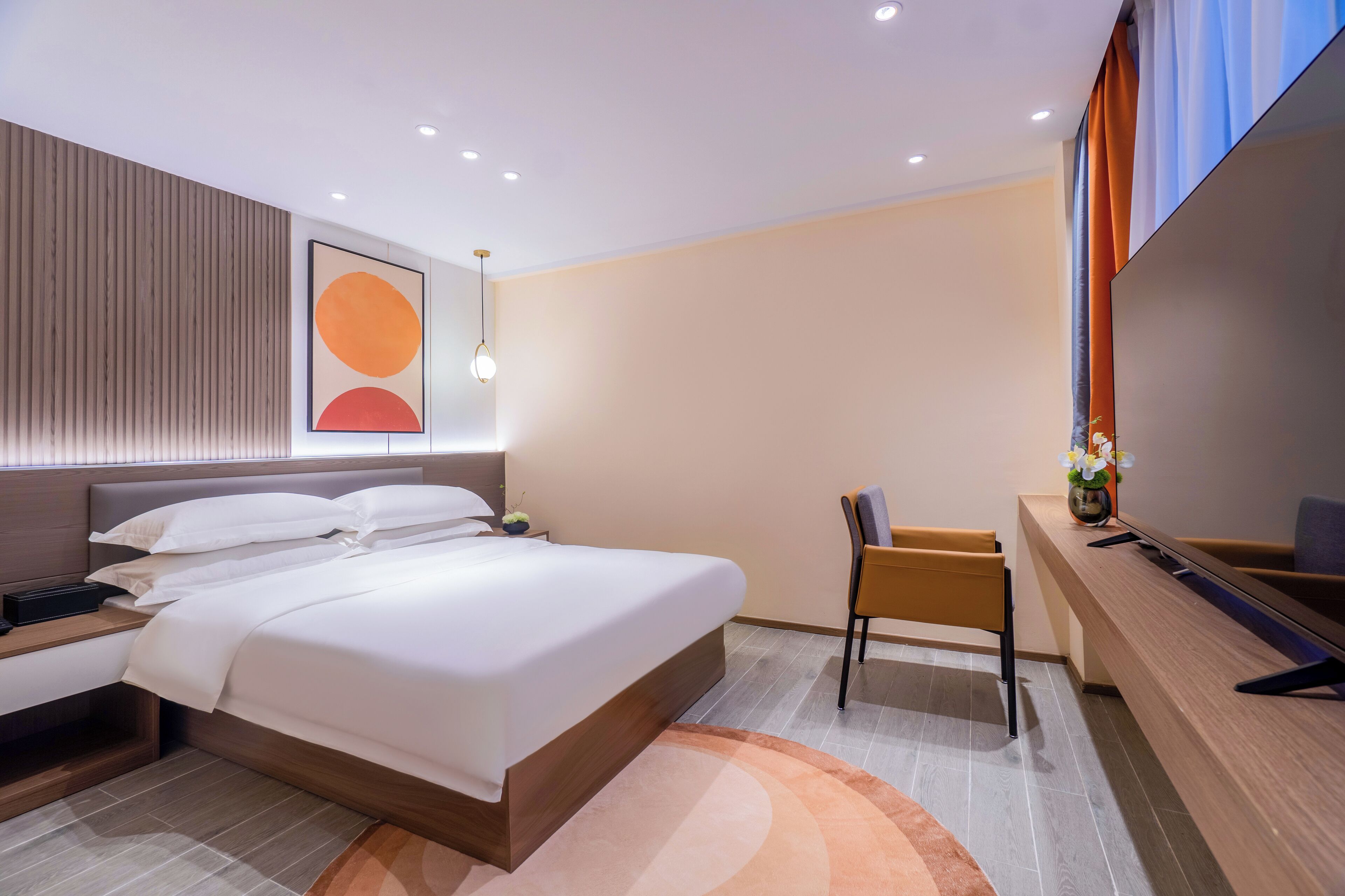 Une chambre d’hôtel moderne dotée d’un grand lit, d’un bureau avec une chaise, d’une télévision et d’une œuvre d’art accrochée au mur.
