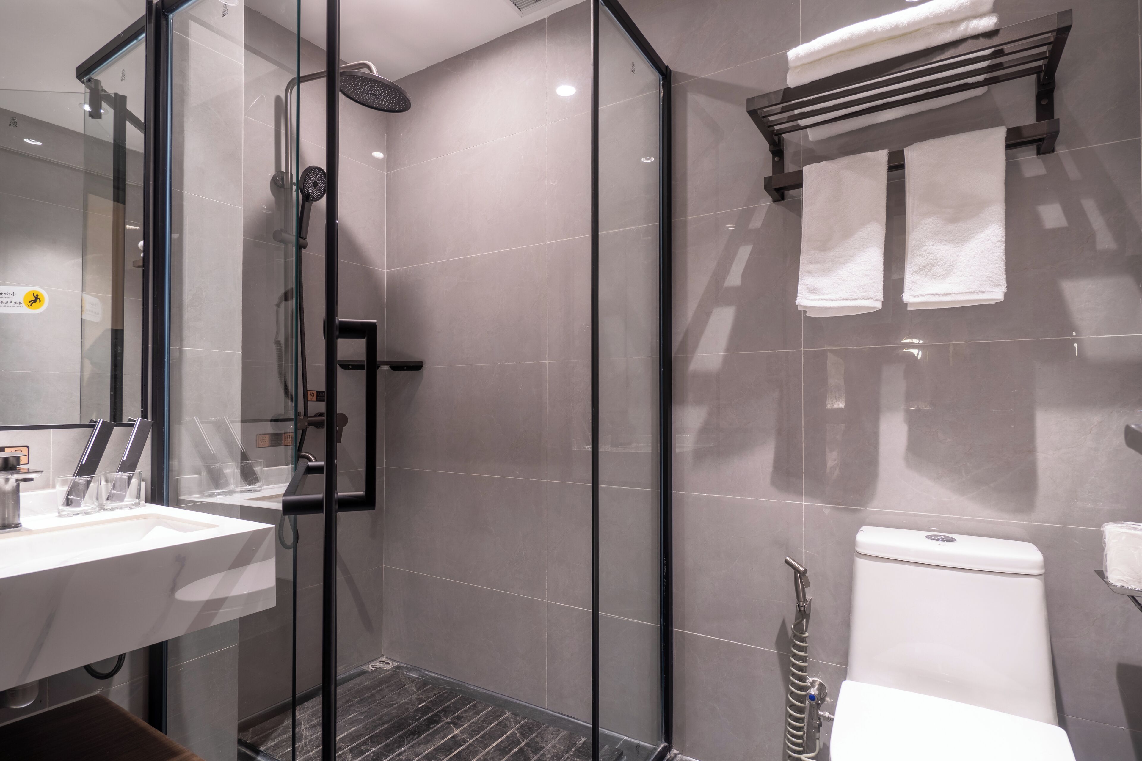 A modern bathroom with a glass-enclosed shower, a white sink, and a toilet.
