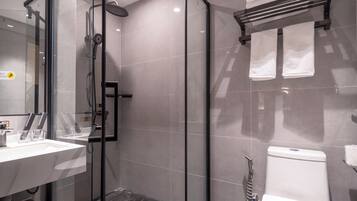A modern bathroom with a glass-enclosed shower, a white sink, and a toilet.