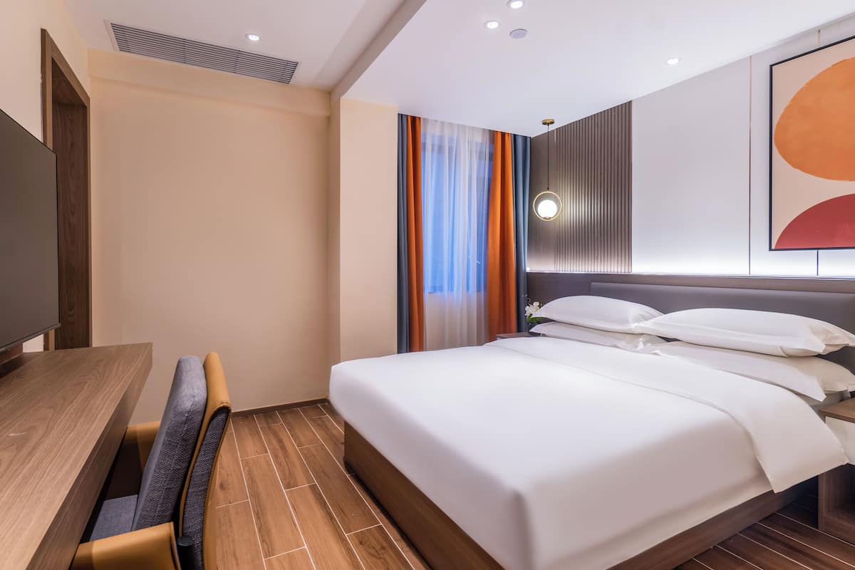 A hotel room with a bed, a desk, and a chair.