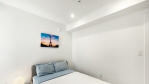 A modern bedroom with a bed, a nightstand, a wall-mounted picture of the Eiffel Tower, and a white ceiling. - Cozy Petworth Stay with Balcony & Courtyard View (Washington)