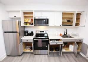 A compact kitchen with a stainless steel refrigerator, a microwave, a stove, and a sink. - Petworth Luxury Unit with Modern Comforts (Washington)