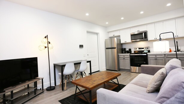 A modern living room with a flat-screen TV, a wooden coffee table, and a sofa. - Petworth Luxury Unit with Modern Comforts (Washington)