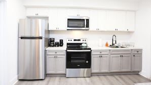A modern kitchen with stainless steel appliances, white cabinets, and a marble countertop. - Petworth Luxury Unit with Modern Comforts (Washington)