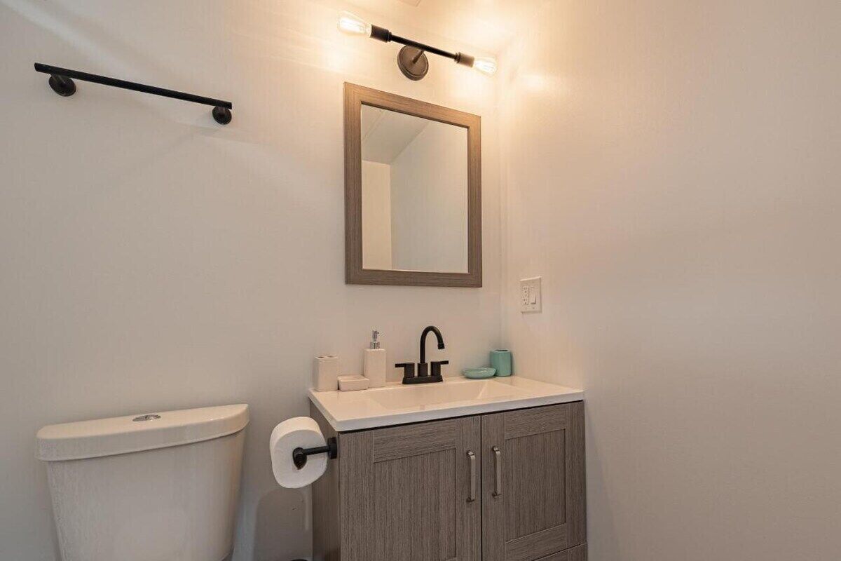 Een badkamer met toilet, wastafel, spiegel en handdoekhouder.