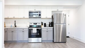 Una cocina moderna con armarios blancos, electrodomésticos de acero inoxidable y suelo de madera.