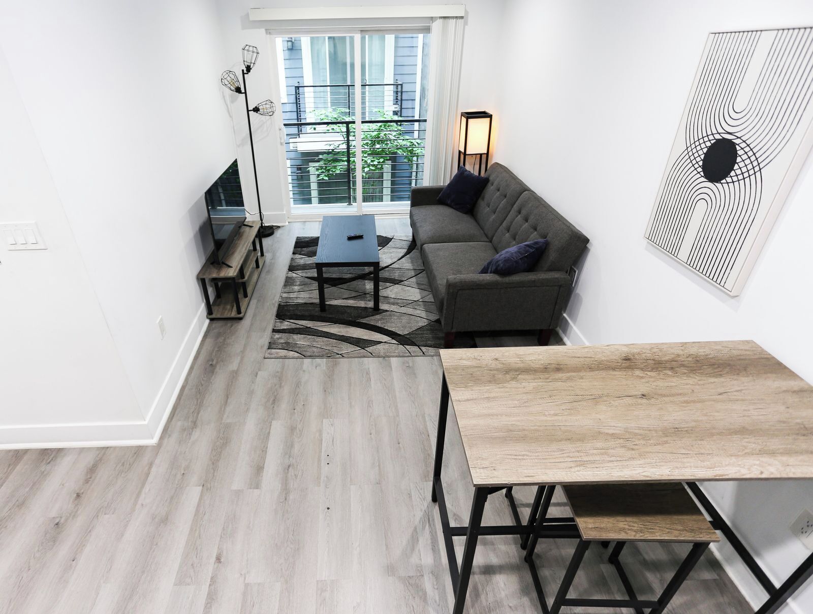 Un salon moderne comprenant un canapé, une table basse, une table à manger et un lampadaire.