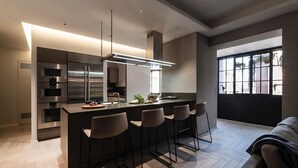 A modern kitchen with a central island, bar stools, and built-in appliances. - Modern Luxury Penthouse with Terrace (Roma)
