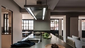 A modern kitchen with a central island, a built-in stove, and a dining area with a sofa. - Modern Luxury Penthouse with Terrace (Roma)