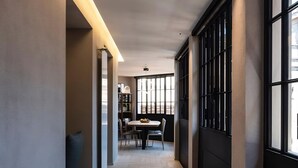 A hallway with a herringbone floor, a dining area with a table and chairs, and large windows with black frames. - Modern Luxury Penthouse with Terrace (Roma)