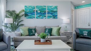 Ein Wohnzimmer mit einer Couch, zwei Beistelltischen, einem Couchtisch und einem Gemälde.